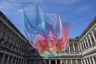 Mulit-coloured netting sculpture by Janet Echelman hangs in the middle of the courtyard of the Palazzo del Senato in Milan.