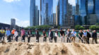 A line of people holding shovels at a ground breaking, with Chicago towers in the background.